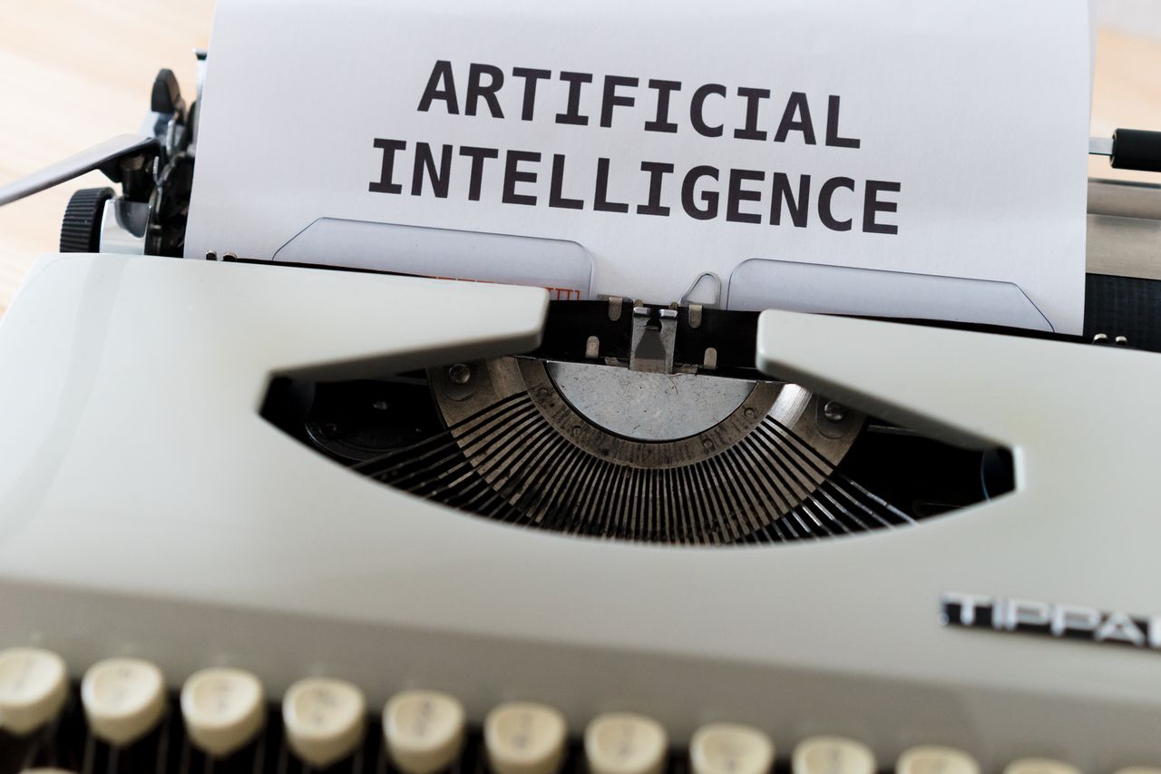 services-04 A close-up of a typewriter showcasing 'ARTIFICIAL INTELLIGENCE' on paper.